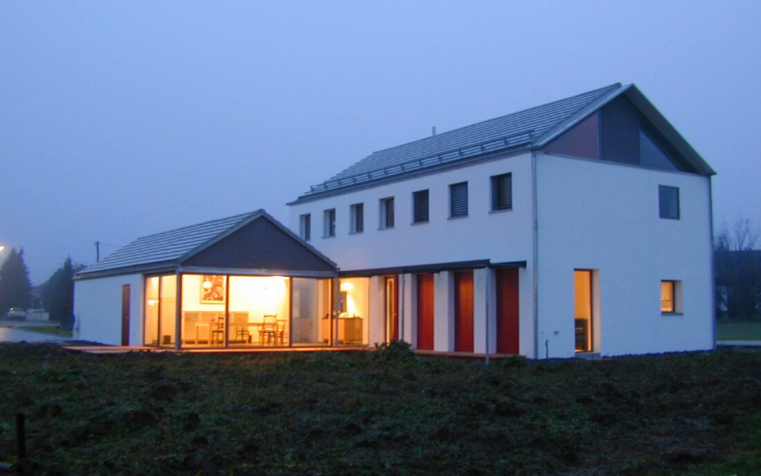 Haus Sonnenberg Kösching – Dämmerungsansicht mit beleuchtetem Essbereich