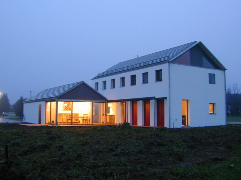 Haus Sonnenberg Kösching – Dämmerungsansicht mit beleuchtetem Essbereich