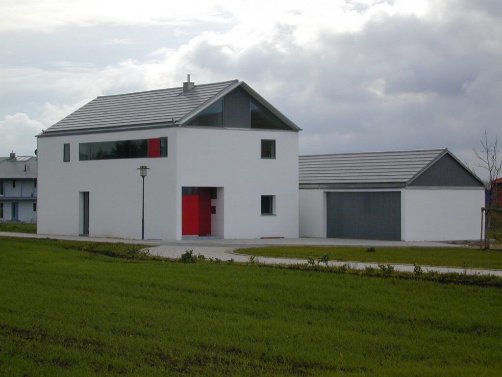 Haus Sonnenberg Kösching – Straßenansicht mit roter Eingangstür und Garage